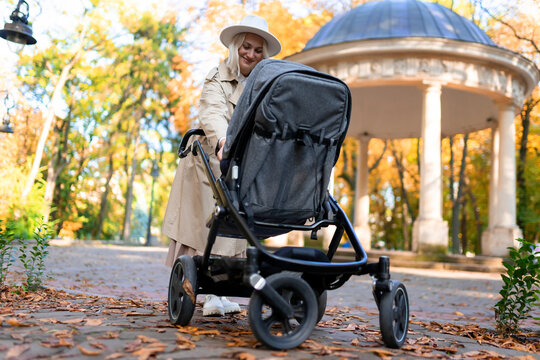 Mother with baby pram walking in autumn park