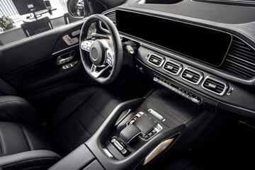 Close-up of the dashboard, speedometer, tachometer and steering wheel with phone setting and volume buttons. Luxurious car interior details.