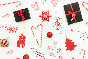 Christmas or New Year pattern. Toys, gift box, candy canes and confetti on white background. Flat lay