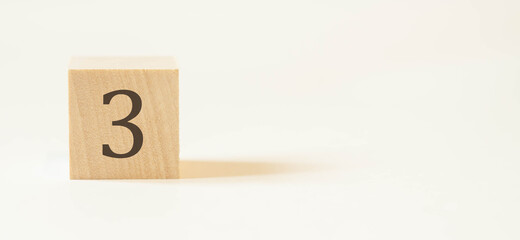 Number three on a wooden cube with a white background.