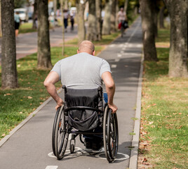 Handicapped man in wheelchair walk at the park alley