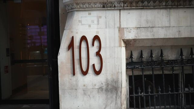 Address number 103 on a marble-looking building next to the entrance
