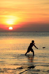 man playing beach flying disc against beautiful sunset sky