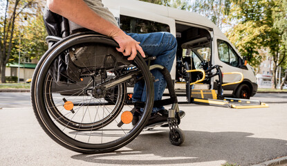 Naklejka premium A man in a wheelchair moves to the lift of a specialized vehicle 