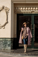 beautiful caucasian brunette woman in a stylish outfit walking down the street in the offseason in a coat and hat
