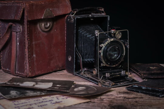 still life with vintage folding photo camera and retro photos