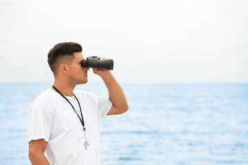 Handsome male lifeguard with binocular near sea