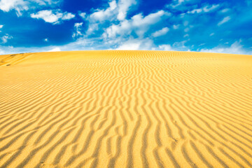 Fototapeta na wymiar Landscape of desert sand dunes and blue sky with clouds over them