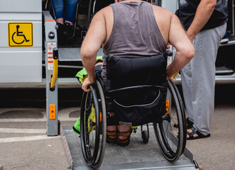 Disabled man on wheelchair using accessible vehicle with lift mechanism.