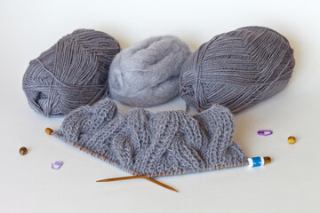 Knitting a warm gray scarf from wool and mohair yarn with bulky knitted braids. The row counter is...