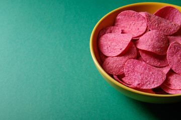 Pink chips in a yellow plate, on a green background