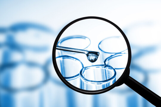 Virus vaccine research laboratory background. Blue fluid pipette drop into glass flask isolated. Test tube transparent liquid. Magnifying glass isolated. Covid-19 coronavirus spread background.