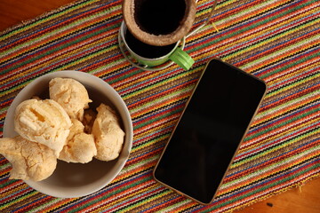 cell phone on the breakfast table, cookies on the plate, cup of coffee, a cell phone on the table