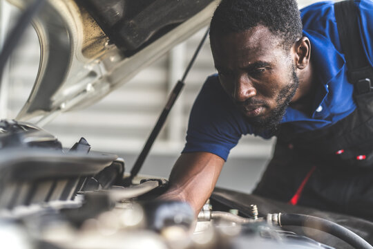 Black male mechanic repairs car in  garage. Car maintenance and auto service garage concept.