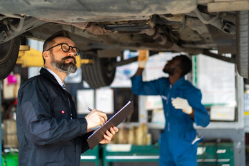 Hipster manger with beard and checklist clipboard talk to Expertise mechanic working Under a...