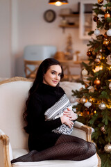young girl, brunette, sitting by the Christmas tree at home