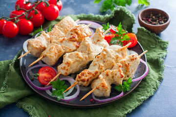Chicken breast kebab baked in the oven on wooden skewers on a plate, horizontal
