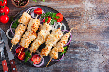 Chicken breast skewers baked in the oven on wooden skewers on a plate, horizontal, copy space