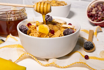Corn Flakes Bowl with Honey, Banana, Berries and Wooden Spoon on white background, Healthy Breakfast, Delicious Food