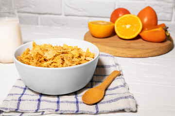 Corn Flakes Bowl with Milk, Persimmon, Orange and Wooden Spoon on white background, Healthy Breakfast