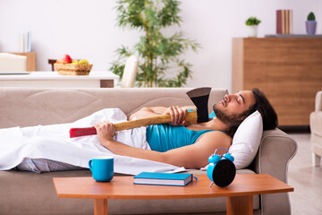 Young man lying on the sofa in time management concept