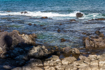 Rocky Beach in Maui Hawaii. Water is sort of choppy with many waves coming into shore. 