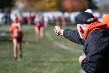A coach points to a runner, encouraging her to run faster.