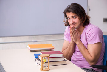 Young male student in the classroom at time management concept