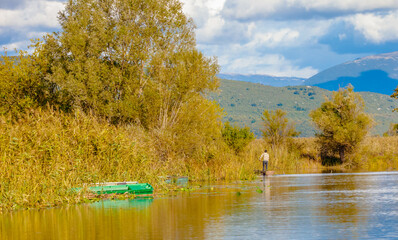 autumn landscape with lake and fisherman