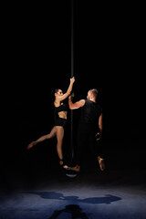 Fototapeta na wymiar Man and woman doing exercises on pylon isolated on black background.Pole dance concept.