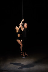 Man and woman doing exercises on pylon isolated on black background.Pole dance concept.