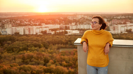 Relaxed woman standing on terrace at sunset