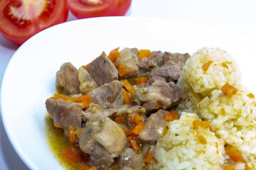 Hot dish of pilaf with meat and rice. White plate, white background top view