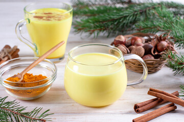 Healthy vegan golden milk, turmeric root, ginger powder, cinnamon on white background. Spices for ayurvedic treatment.