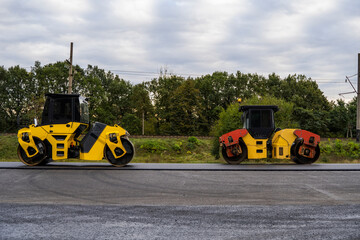 Asphalt road roller with heavy vibration roller compactor press new hot asphalt on the roadway on a road construction site. Heavy Vibration roller at asphalt pavement working. Repairing.
