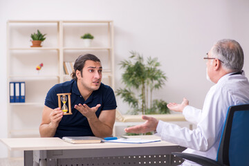 Young male patient visiting old doctor in time management concep