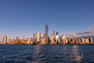 Naklejka premium Lower Manhattan Skyline along the Hudson River in New York City Shining during a Sunset