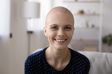 Head shot portrait smiling hairless woman making video call, looking at camera, sitting on couch at...