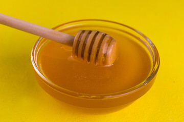 Floral honey in a bowl on a yellow background.
Close-up.
