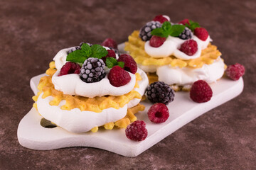 Waffles with airy protein cream and fresh berries on a brown background.