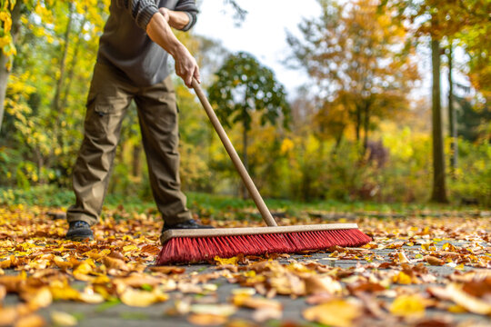 Mit gro&szlig;em Besen Bl&auml;tter im Herbst zusammen fegen