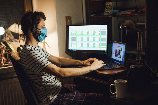 man wearing a protective mask working at home at the computer during quarantine virus epidemic disease