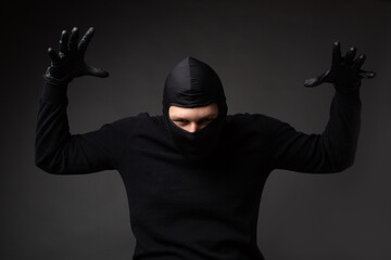 burglar in black mask with raised hands