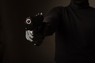 a gun in the hands of a robber on a black background