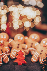 Many Christmas cookies in the form of gingerbread men depicting people celebrating the New Year in the forest near the Christmas tree