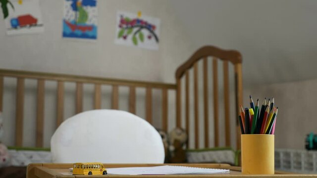 Close-up Toy Yellow School Bus Paper and Pencils on Empty Desk in Room. Education at Home. Blurred Background Pictures Bed. 2x Slow motion 60 fps 4K