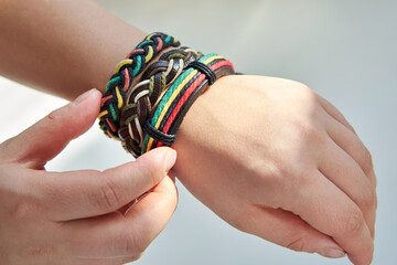 Three bracelets made of fabric and leather ropes on a woman's hand.