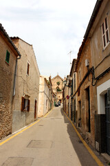 Fototapeta na wymiar Typical narrow Spanish street. At the end of the street is the Cathedral of San Salvador. Arta city, Mallorca island.