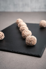 Vegetarian truffles from dates and white sesame on a slate Board