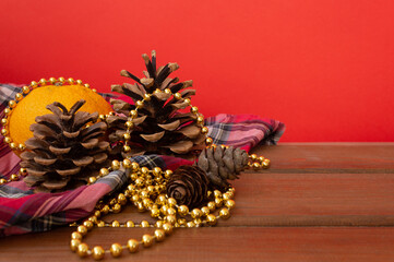 Cones with Christmas decorations on a wooden table and a red background. New Year mood